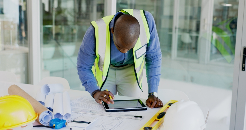 Construction site manager using cloud-based ERP on a tablet for real-time project tracking and NRS tax compliance in Nigeria.